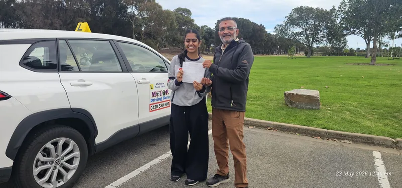 Instructor and learner holding a certificate beside the school SUV