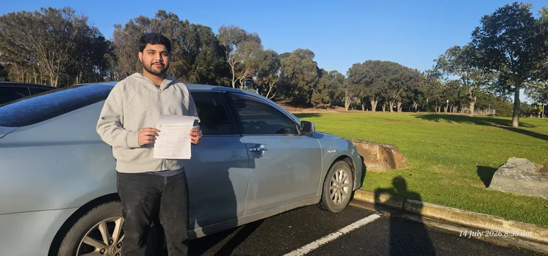 Learner holding a certificate beside a silver car in Adelaide
