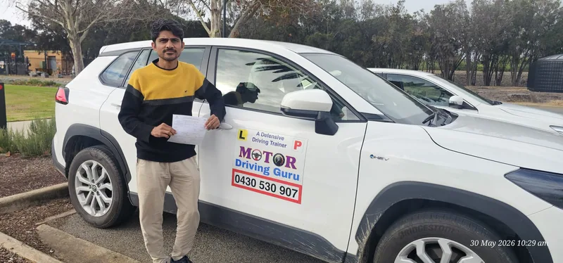 Learner in a yellow and black jumper beside the Motor Driving Guru SUV